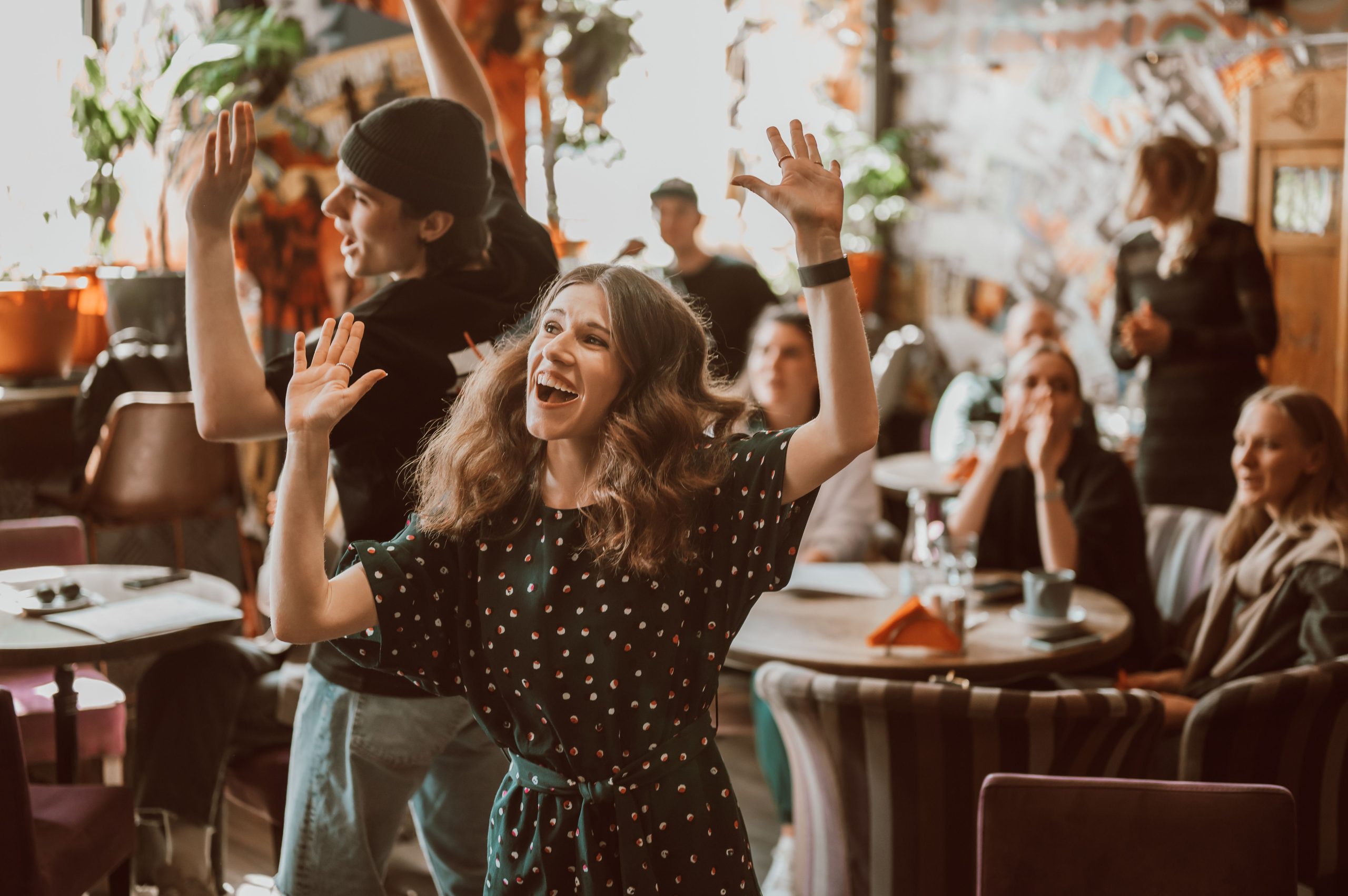 A lively indoor celebration featuring a joyful young couple dancing among friends.