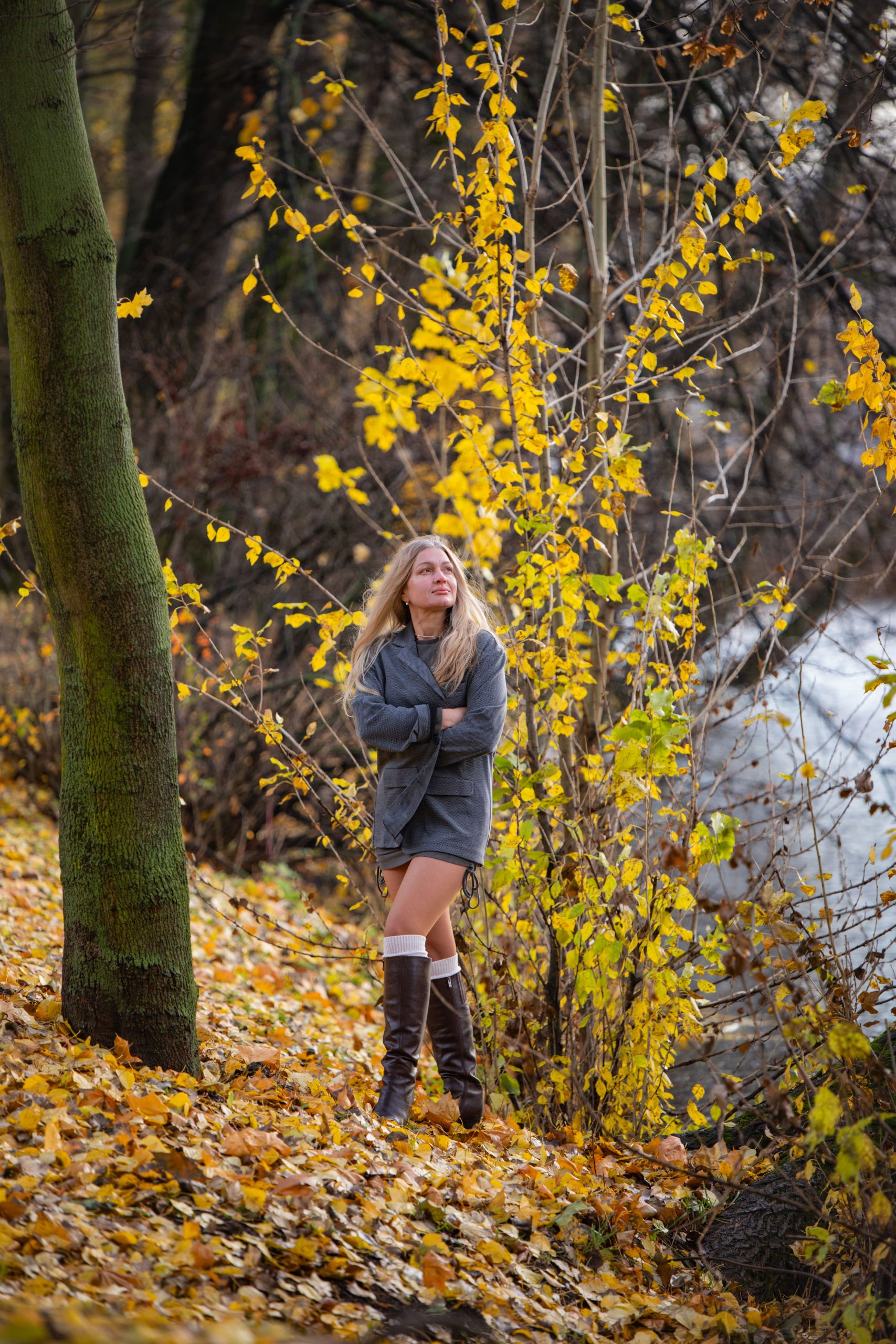 A young woman walks through a colorful autumn forest, surrounded by yellow leaves.